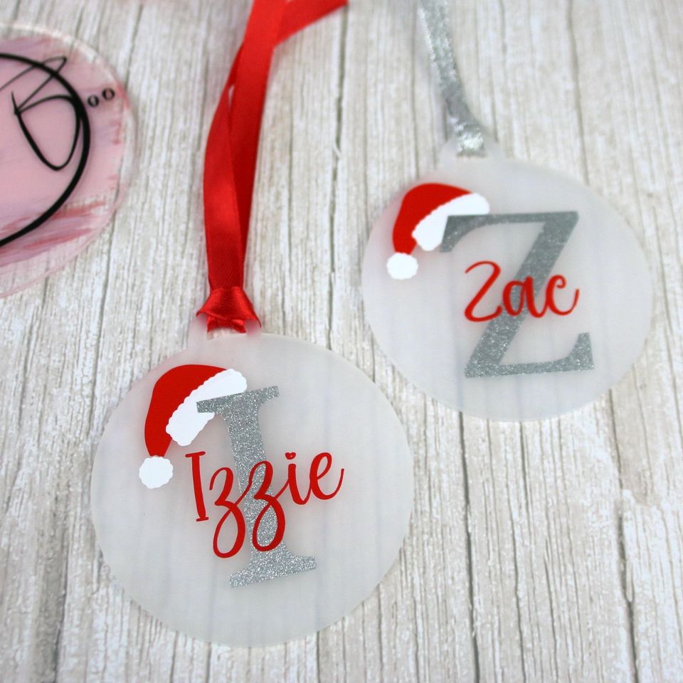 Flat acrylic baubles with glitter initials, Santa hats and the names “Izzie” and “Zac”