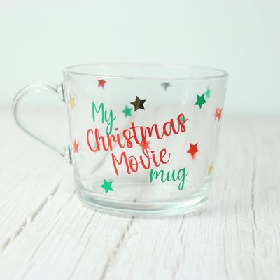 Clear glass mug lettered “My Christmas Movie Mug” with red, green and gold stars